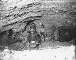 Miners thawing frozen ground with steam in an underground gold mine lit by candlelight, Gold Hill
